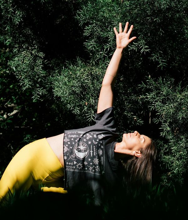 Woman in a calm yoga pose in a dark room with warm light.